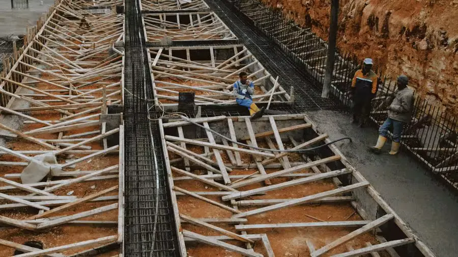 Construction workers at a site with wooden framework in progress, showcasing development.