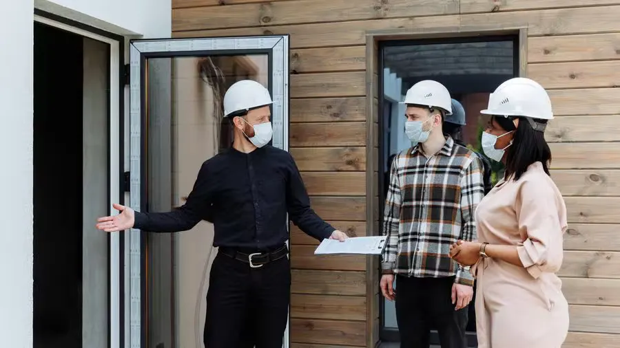 Real estate agent with clients viewing a new house during COVID-19 wearing safety gear.